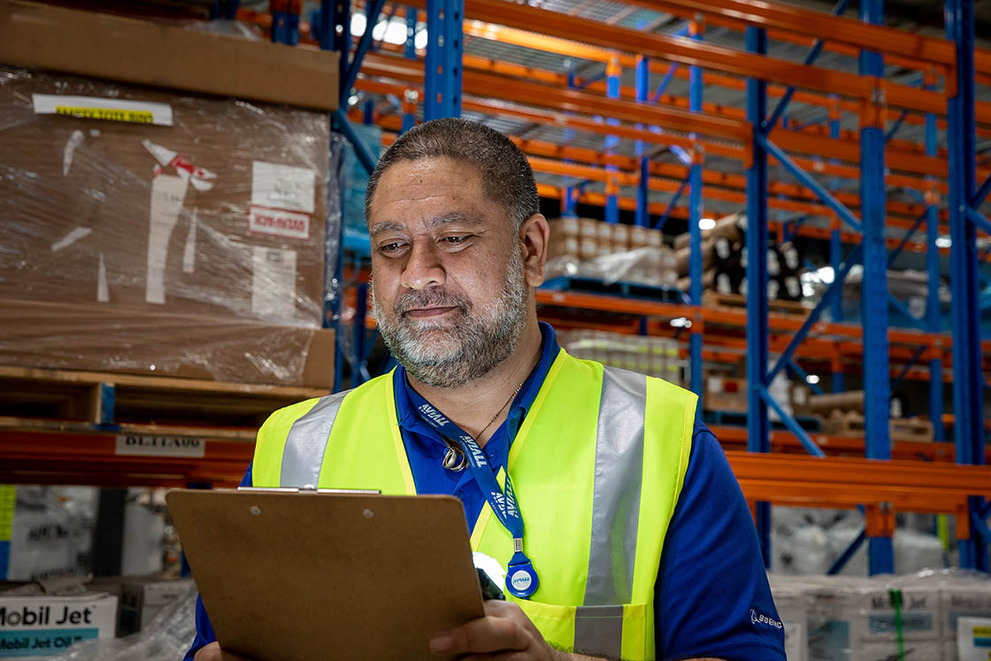 Man in high visibiity vest with clipboard in warehouse setting