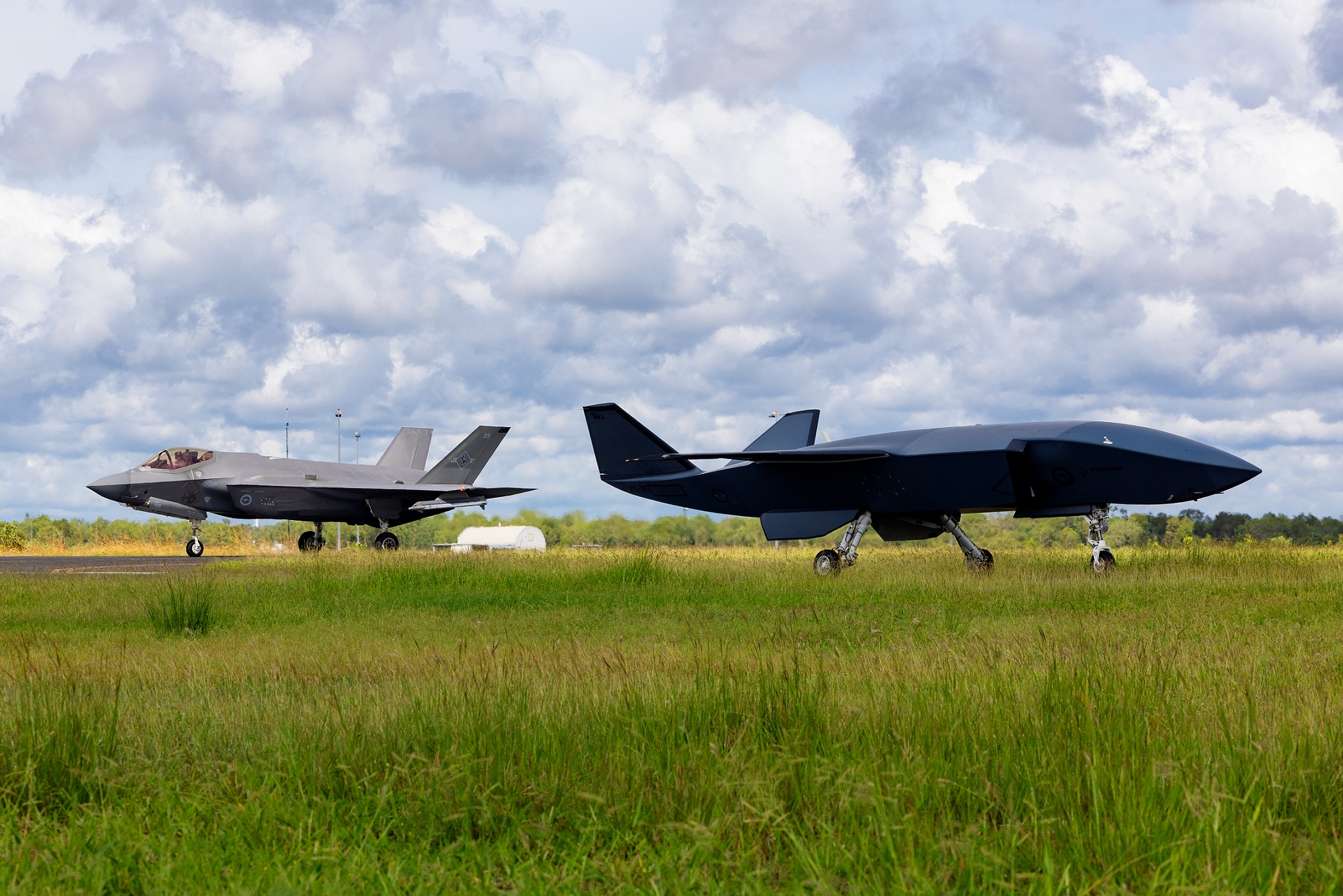 An MQ-28A Ghost Bat on the tarmac as an F-35A Lightning II taxis after a sortie during Exercise Carlsbad at RAAF Base Tindal.